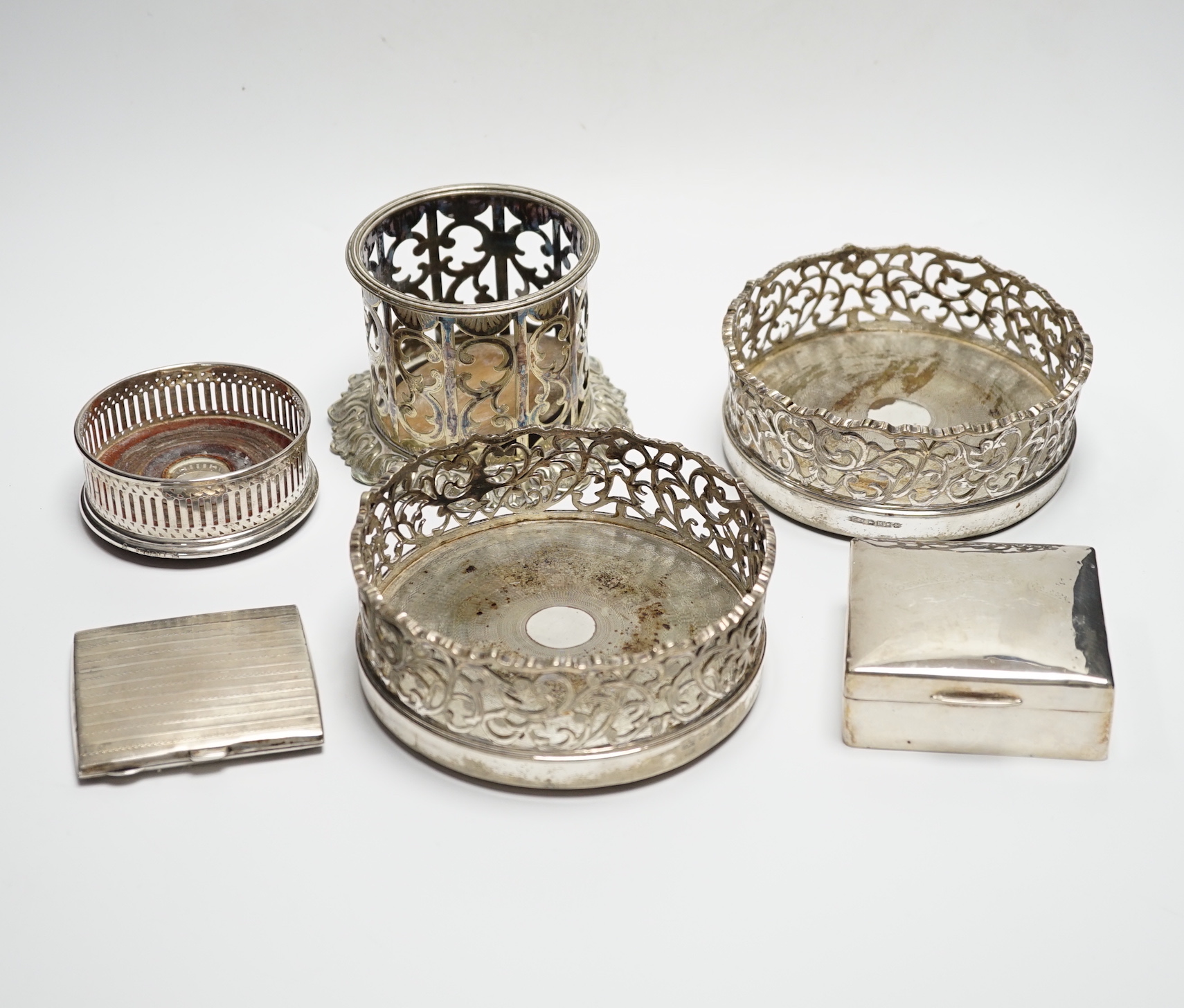A George V silver cigarette case, 82mm, a similar silver mounted cigarette box, a modern silver mounted small wine coaster and three silver plated wine coasters including a pair.